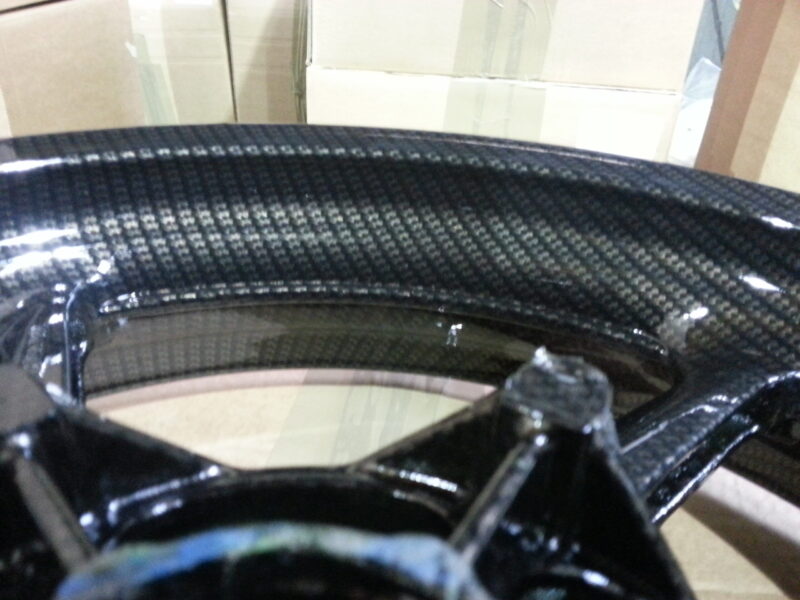Motorbike alloy wheels coated in carbon fibre painted black