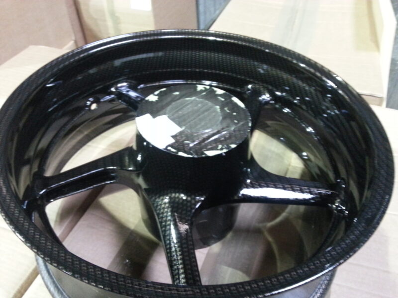 Motorbike alloy wheels coated in carbon fibre painted black