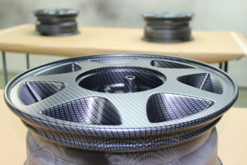 Car alloy wheels coated in carbon fibre painted magenta