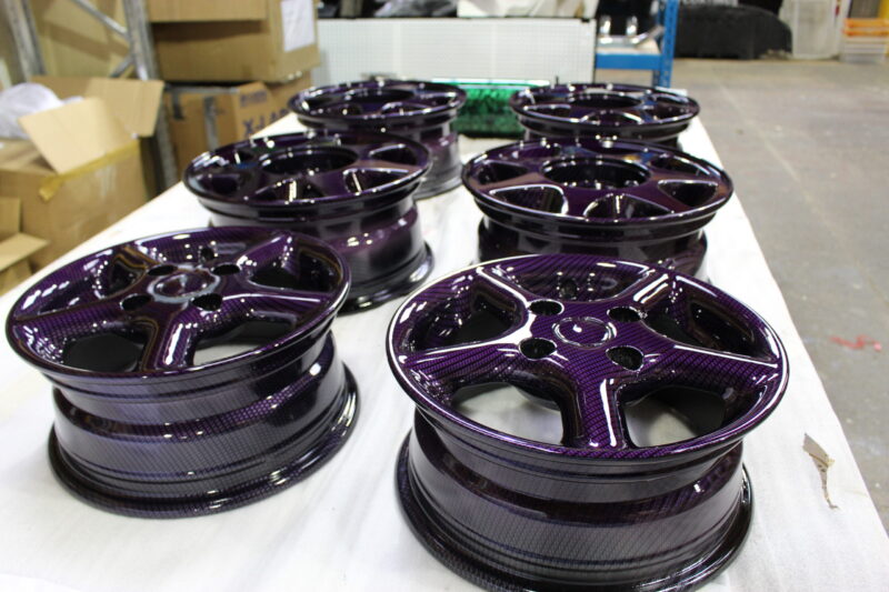 Car alloy wheels coated in carbon fibre painted magenta