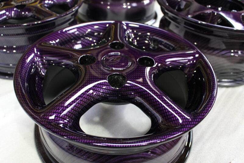 Car alloy wheels coated in carbon fibre painted magenta