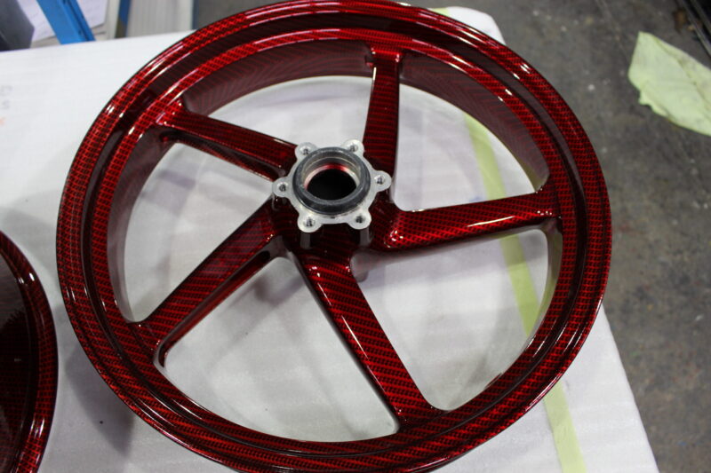 Motorbike alloy wheels coated in carbon fibre painted dark red