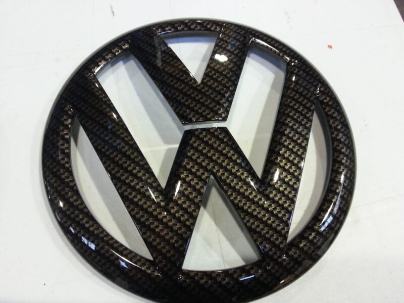 VW car badge coated in carbon fibre hydrographic film painted black