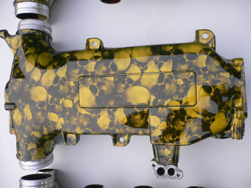 Car engine part coated in skull and carbon fibre painted yellow