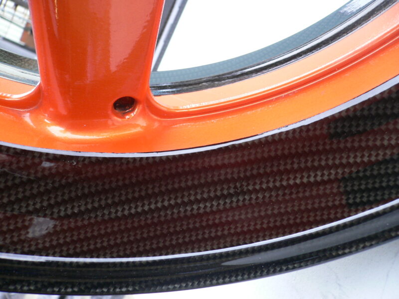 Motorbike alloy wheels coated in carbon fibre painted black and orange