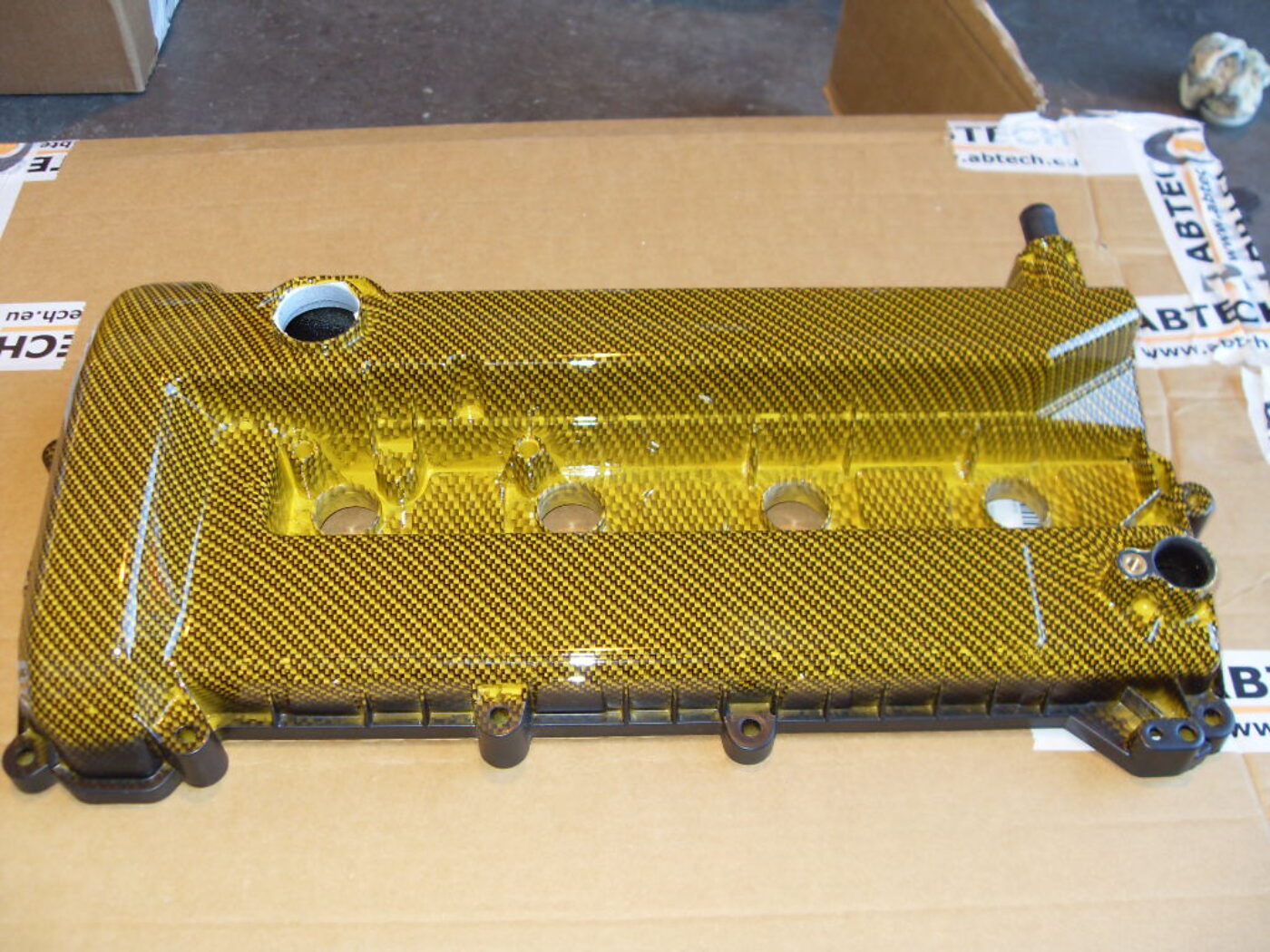 Car engine parts coated in carbon fibre painted yellow