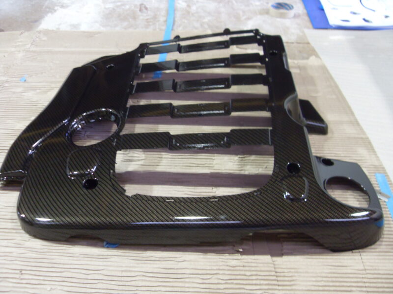 Car engine cover coated in carbon fibre hydrographic film painted black