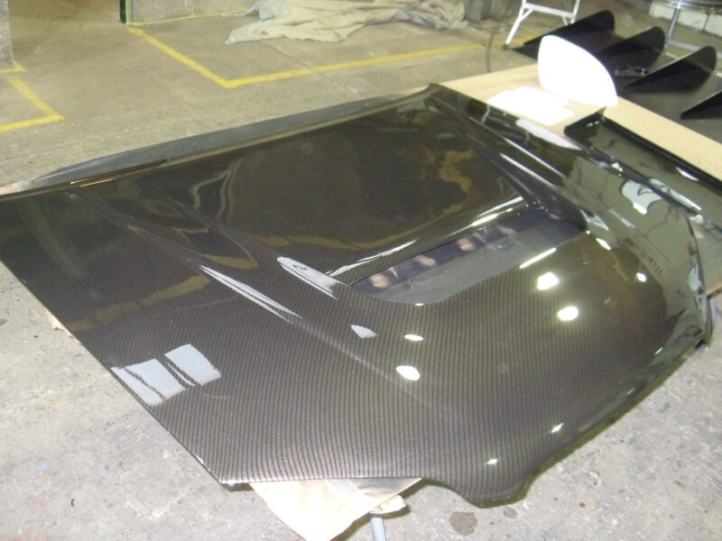 Car hood coated in carbon fibre hydrographic film painted black