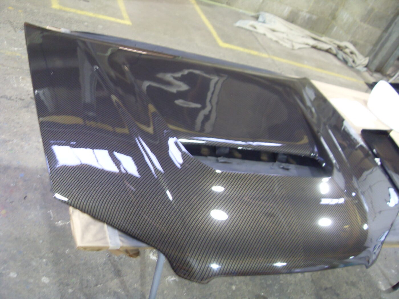 Car hood coated in carbon fibre hydrographic film painted black