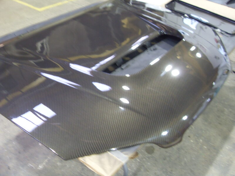 Car hood coated in carbon fibre hydrographic film painted black