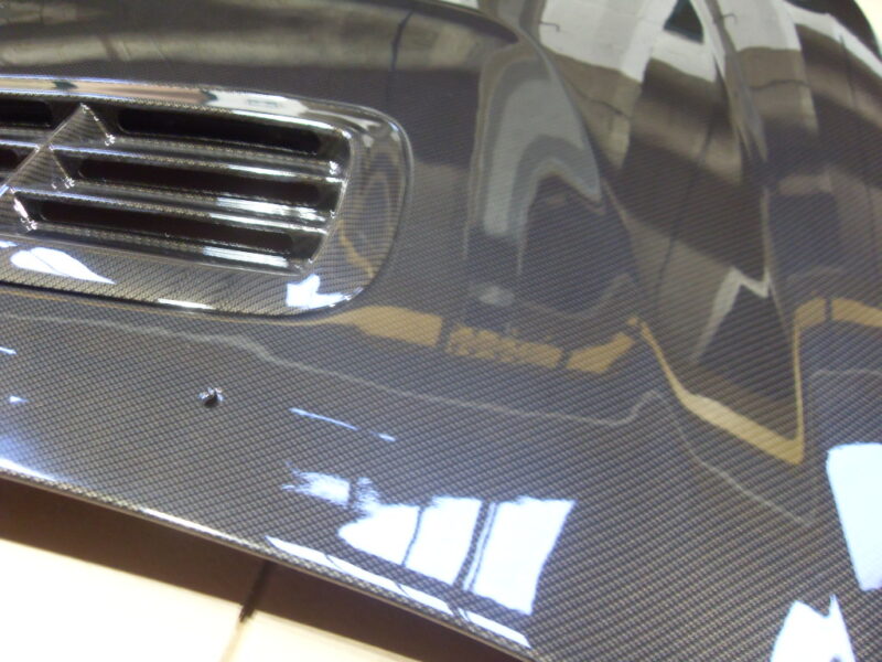 Car hood coated in carbon fibre hydrographic film painted grey