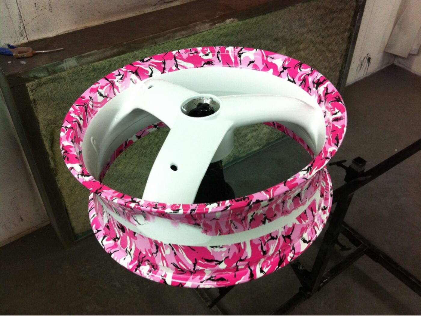 Pink abstract hydrographic film over white painted motorbike alloy wheels