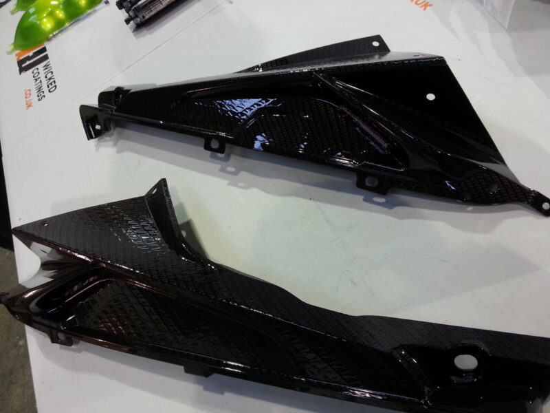 Motorbike parts coated in carbon fibre hydrographic film painted black